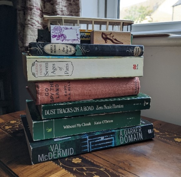 Stack of books topped with a model bus and two rubber stamps