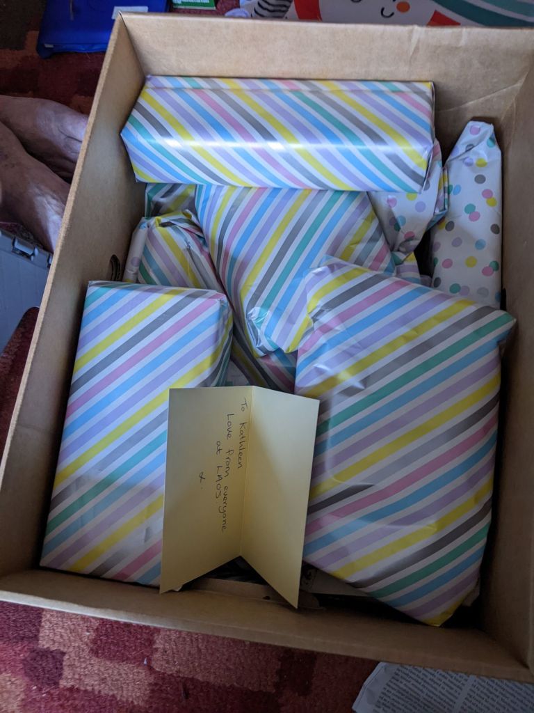A cardboard box filled with small presents wrapped in striped paper 